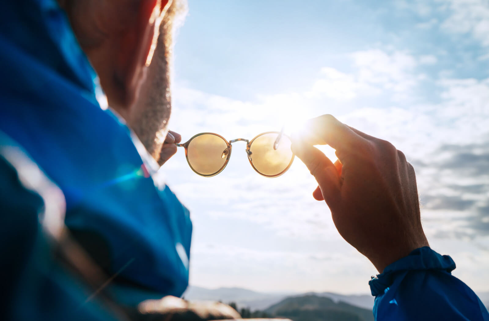 A man outdoors putting on his UV protection sunglasses