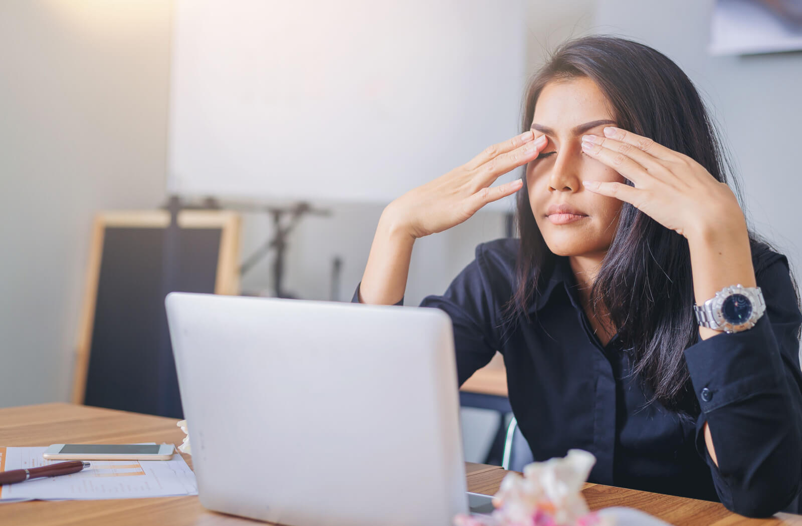 woman working on the laptop and rubbing her dry eyes
