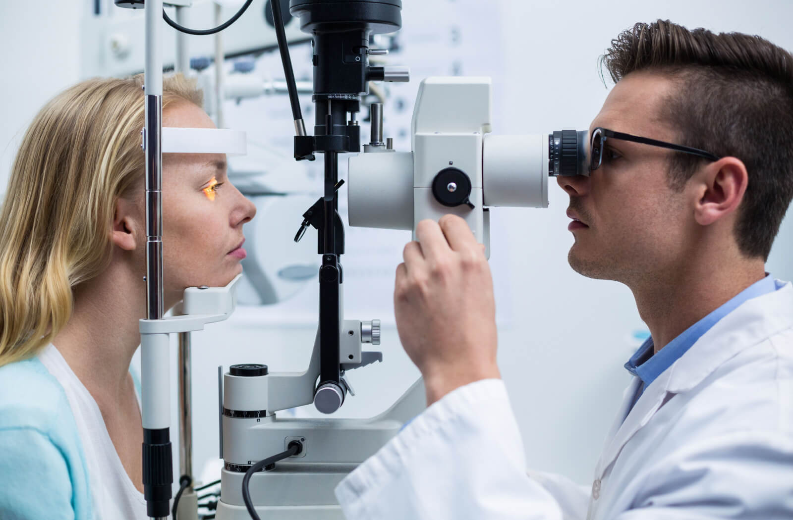 An optometrist performing a slit-lamp exam on his patient to find signs of eye problems.