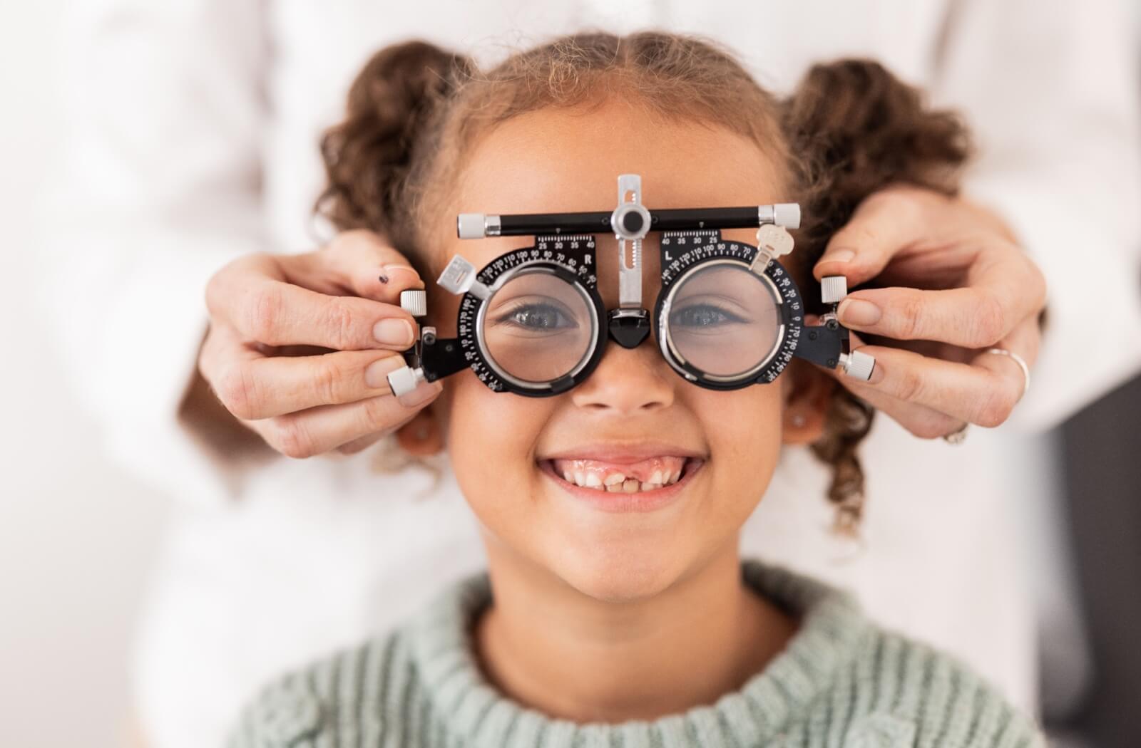 A young girl smiling during her eye exam.