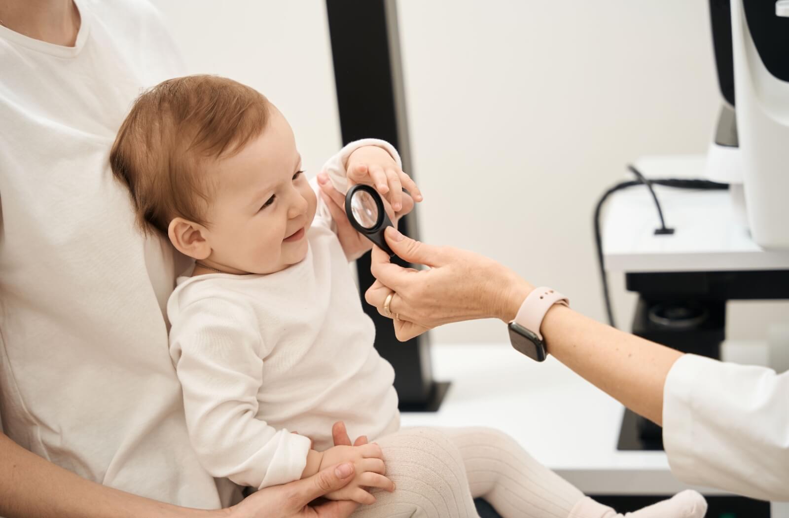 An infant sitting on their parent's lap during their first eye exam appointment.