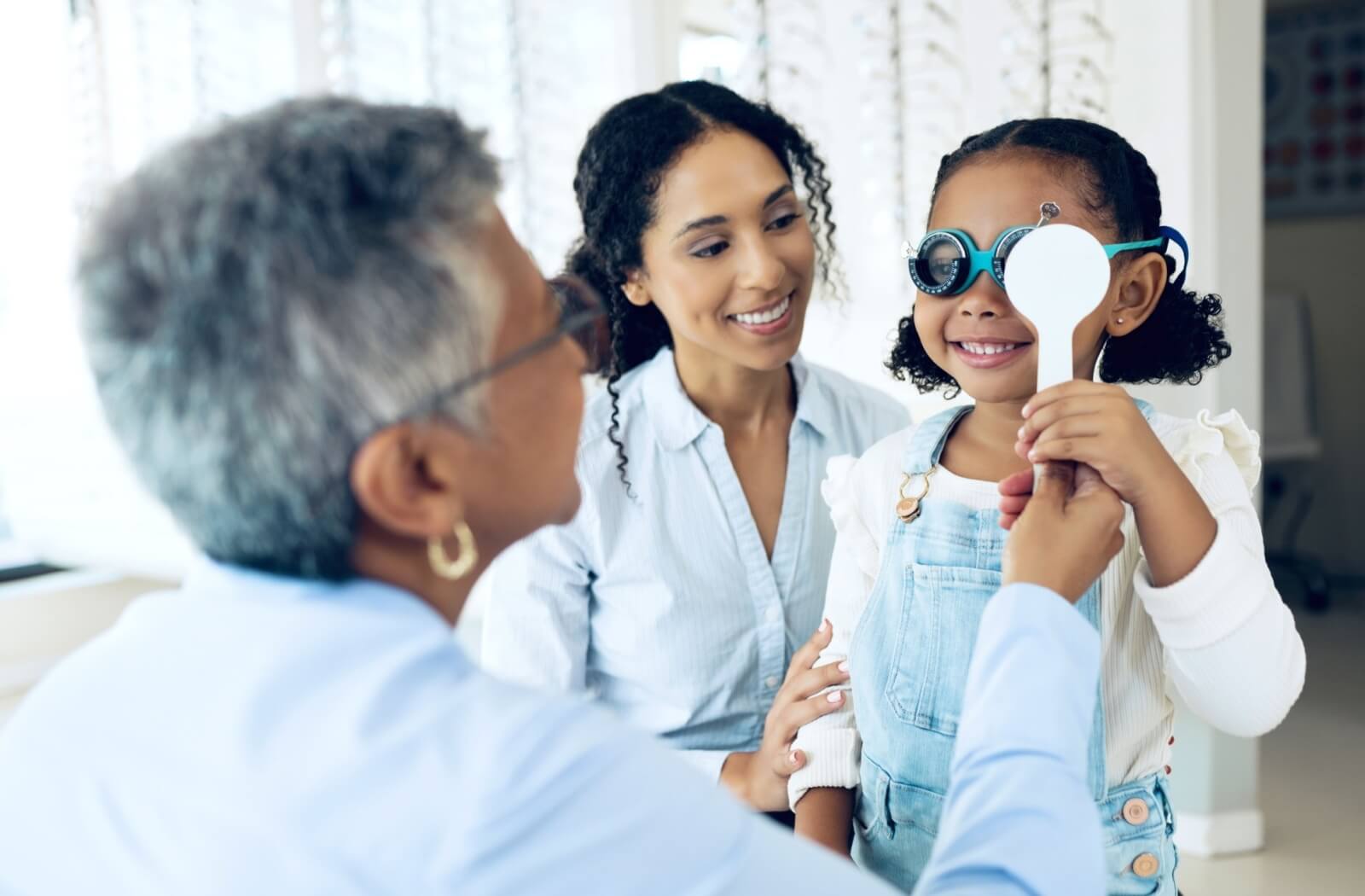 Young patient and her mother with eye doctor at clinic for eye exam to help address learning difficulties.