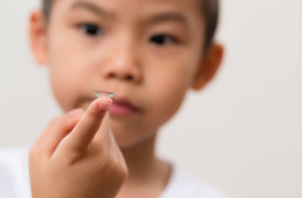 A child holds up a myopia management contact lens before inserting it in their eye.