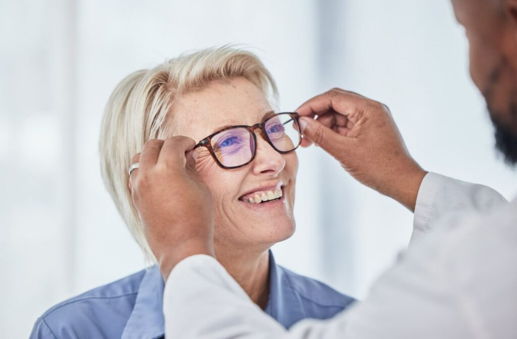 An older adult smiling while being fitted for a new pair of glasses.