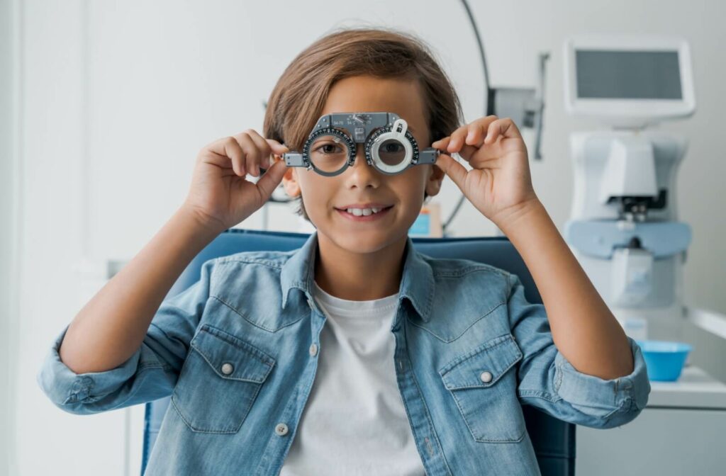 A child smiling while wearing a trial frame during an eye exam.